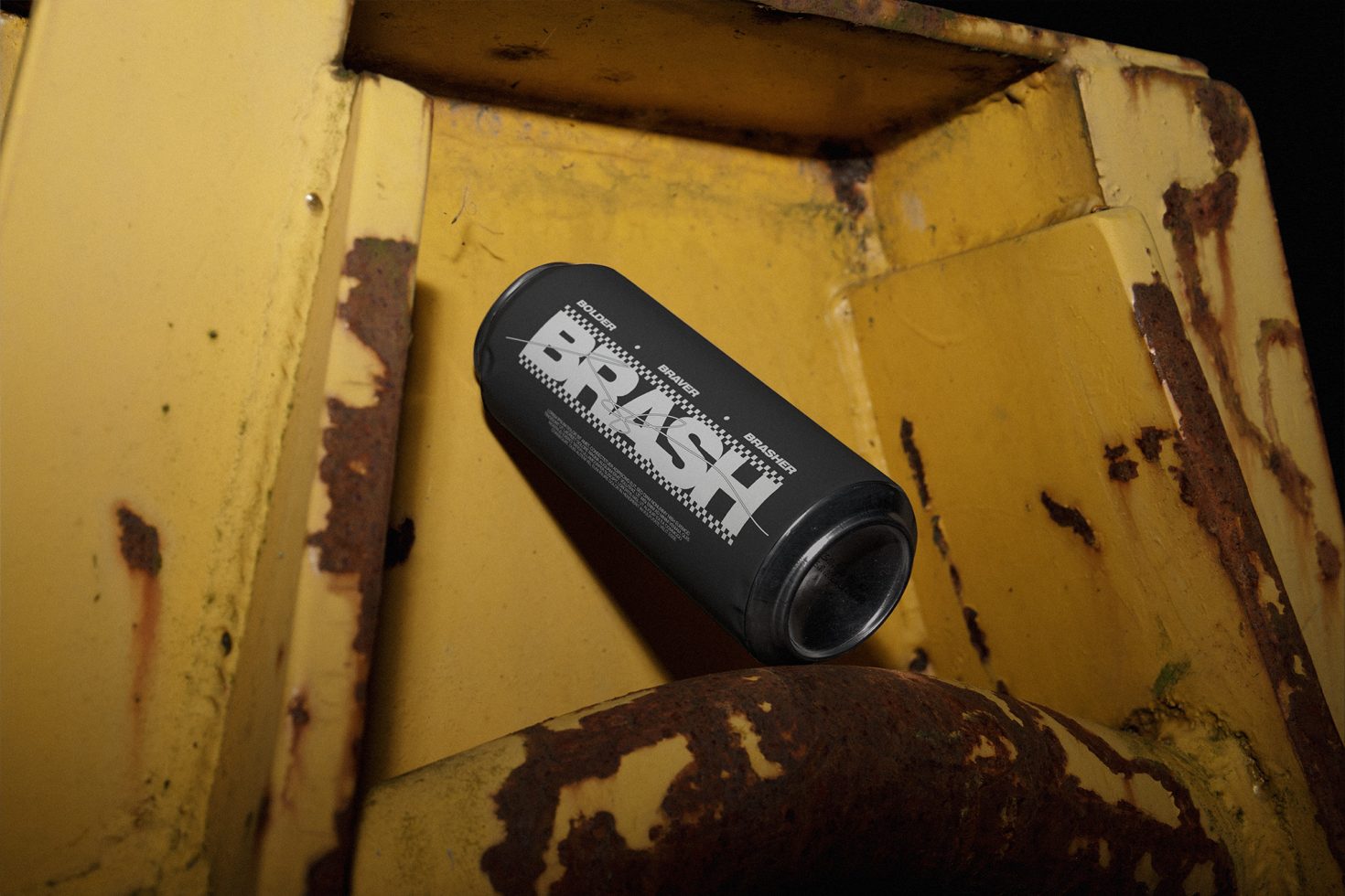 Black beverage can with bold typography on a rusty yellow surface, urban mockup for drink branding designs.